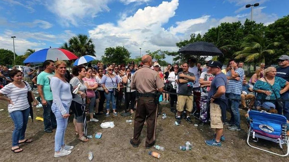 A police officer addresses a group of people waiting in line at the food assistance center at Amelia Earhart Park in Hialeah on Saturday, Oct. 14, 2017. On Saturday, food assistance centers in Miami-Dade and Broward closed after overwhelming response.