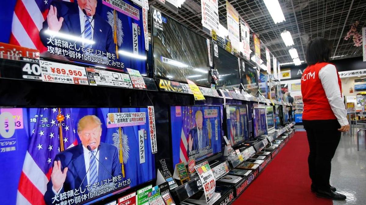 A salesclerk stands in front of flat-panel TVs showing Republican's front-runner candidate Donald Trump in a news program on the U.S. presidential election’s Super Tuesday at an electronics store in Tokyo, Wednesday, March 2, 2016. After the Super Tuesday primaries and caucuses in a dozen states, Trump and Democrat candidate Hillary Clinton had tightened their grasp on their party’s presidential nominations.