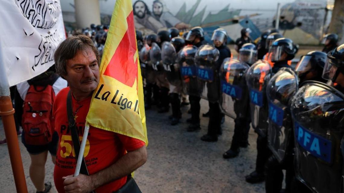 A protester stands holding a flag beside police line during a general strike on the outskirts of Buenos Aires, Argentina, Thursday, April 6, 2017. A national strike, the first in the era of Mauricio Macri's government, has forced all public transports services to not work Thursday.
