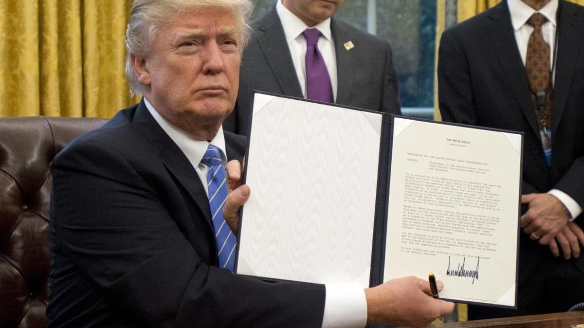 U.S. President Donald Trump shows the Executive Order withdrawing the US from the Trans-Pacific Partnership (TPP) after signing it in the Oval Office of the White House in Washington, DC on Monday, January 23, 2017.