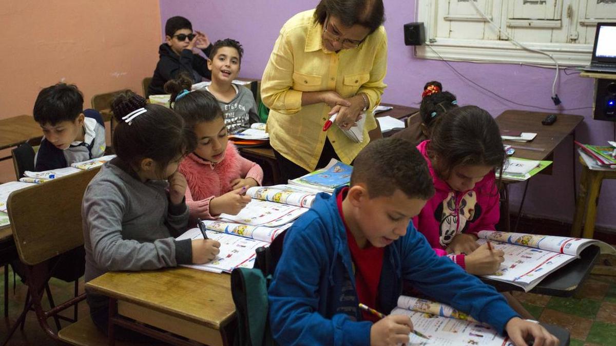 In this Feb. 5, 2016 photo, teacher Graciela Lage helps students during an English lesson at the Cuban School of Foreign Languages in Havana, Cuba.