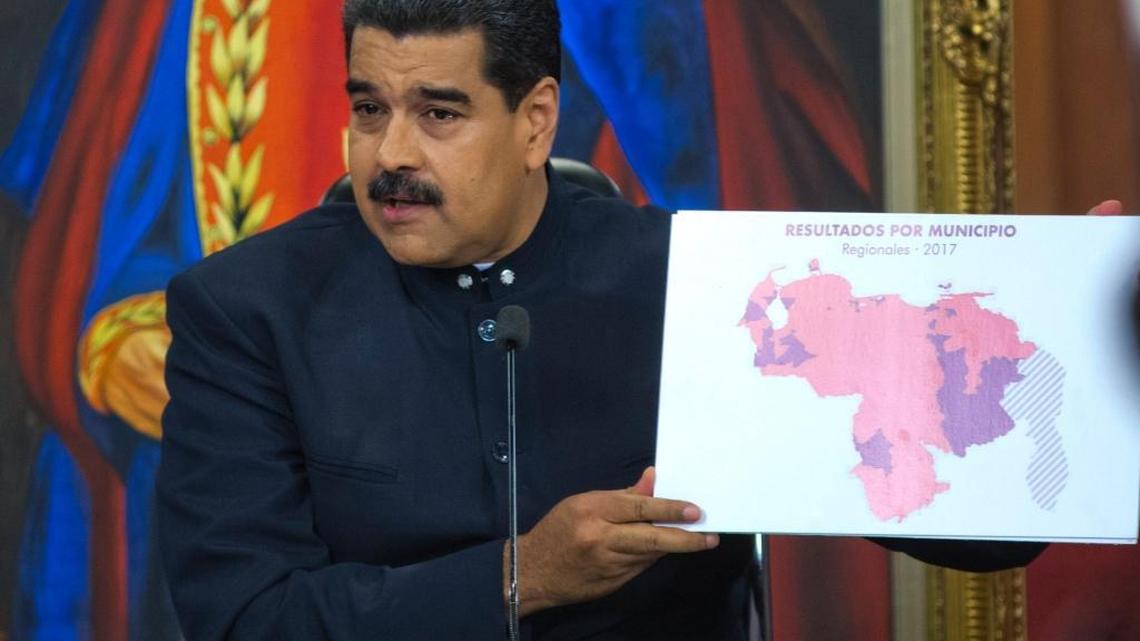 Venezuela's President Nicolas Maduro holds up a map with the Venezuelan regions highlighted in red where pro-government candidates were victorious, during a press conference at the Miraflores presidential palace, in Caracas, Venezuela, Tuesday, Oct. 17, 2017. Maduro defended the results of Sunday's gubernatorial elections and said that those who report fraud are lying.