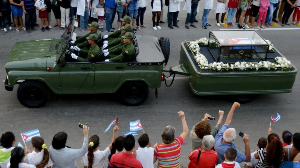 People wave Cuban flags as the ashes of Cuban leader Fidel Castro — placed in a small coffin covered by a Cuban flag — depart from the town of Santa Clara, Cuba, on Thursday, Dec. 1, 2016. Castro’s ashes will have a final resting place in the eastern city of Santiago.