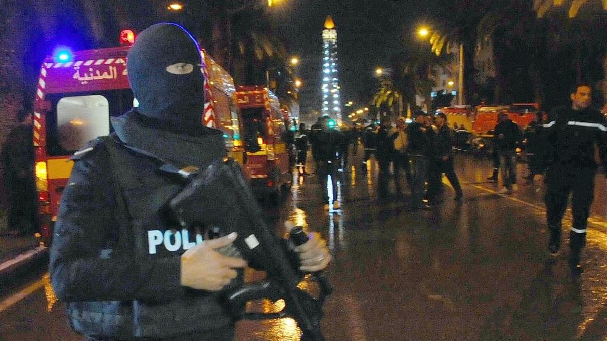 A hooded police officer prevents media from aproaching the scene of a bus explosion in the center of the capital, Tunis, Tunisia, Tuesday, Nov. 24, 2015. An explosion struck a bus carrying members of Tunisia's presidential guard in the country's capital Tuesday, killing at least 12 people and wounding more than a dozen others in what the Interior Ministry called a “terrorist act.”