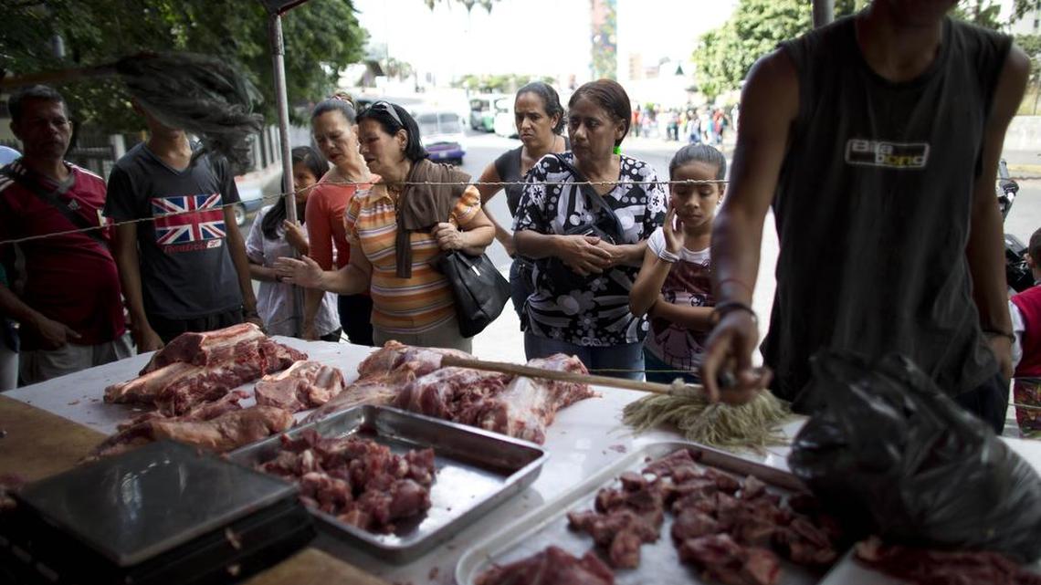 People gather at a Caracas street stand to buy meat.