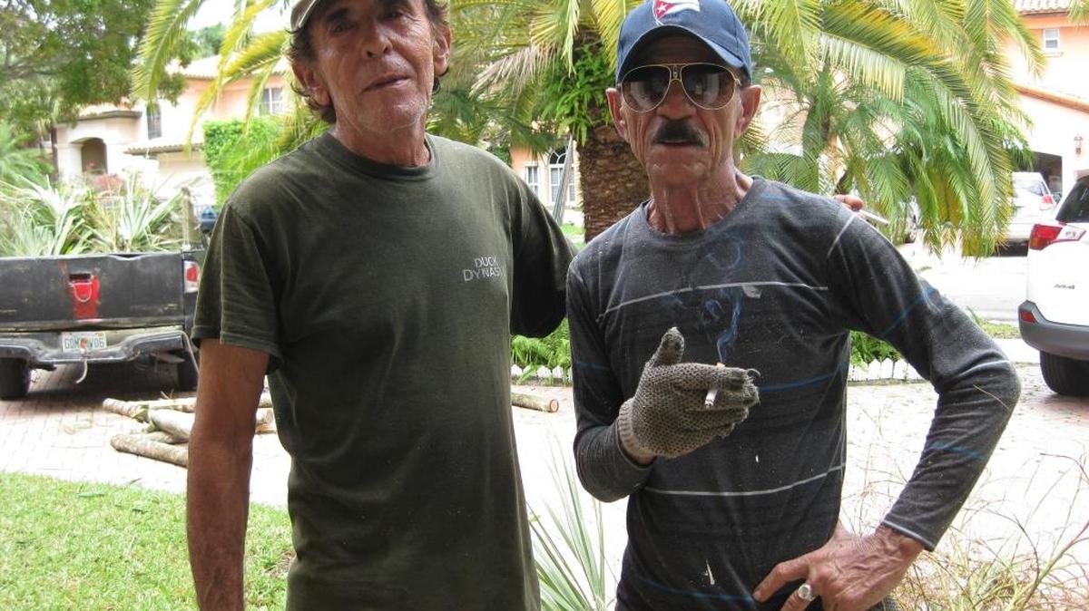 Isidro Batista and Pascual pause for a cafecito break while putting up shutters and trimming palm trees in Miami Lakes.