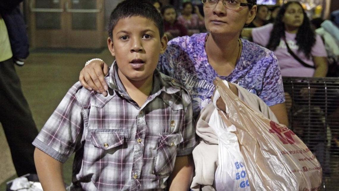 In this May 29, 2014, file photo, Maria Eva Casco, left, and her son Christian Casco of El Salvador, sit at at the Greyhound bus terminal, Thursday, May 29, 2014, in Phoenix. Central American families arrested in Texas will continue to be flown to Arizona, and hundreds of unaccompanied minors a day are being shipped to a federal detention center in the southern part of the state, Gov. Jan Brewer’s spokesman says.