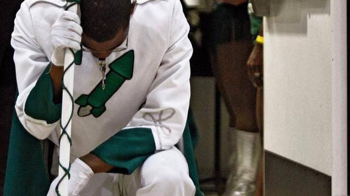 In this 2009 file photo, drum major Andre Young kneels in prayer in the doorway prior to performing with Miami Central High School band.