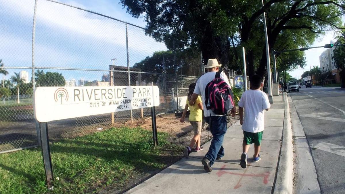 People walk in front of Riverside Park located on SW 7th Ave between 3rd and 4th streets in Little Havana on Tuesday, Oct. 27, 2015.