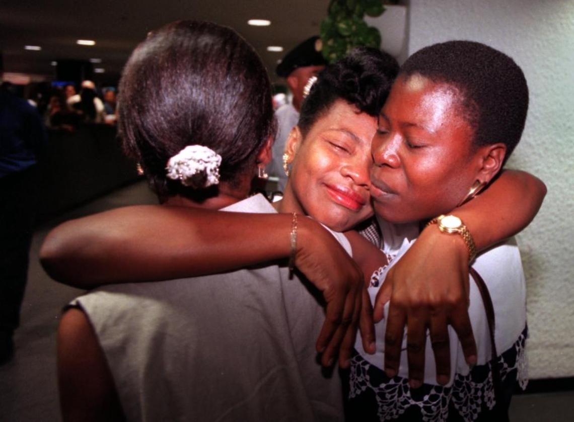 Marie-Esperancia Fortin, from Naples, Florida, hugs her two sisters after they arrived at Miami International Airport from Haiti in 1996.