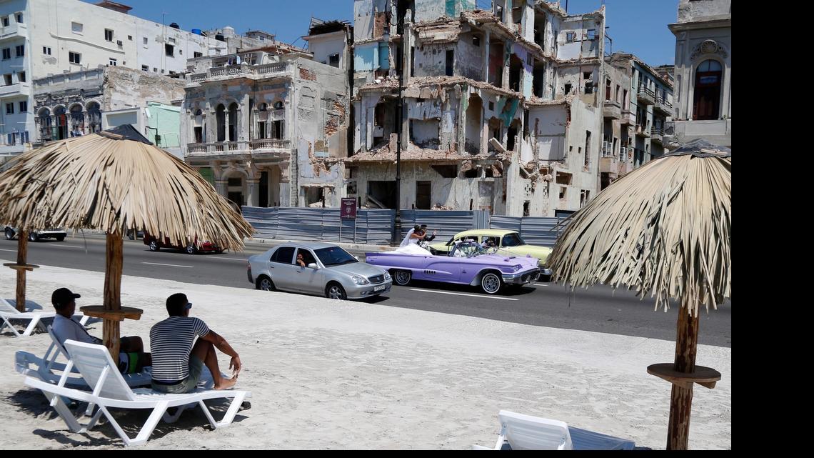 
ART IN HAVANA?: People sit on deck chairs on an artificial beach as a bride and groom ride a classic American convertible car on the Malecon in Havana, Cuba. The artificial beach is part of a collective artistic intervention named (R)Behind The Wall(R)for the 2015 Havana Biennial,which started on May 22 and runs through June 22.
