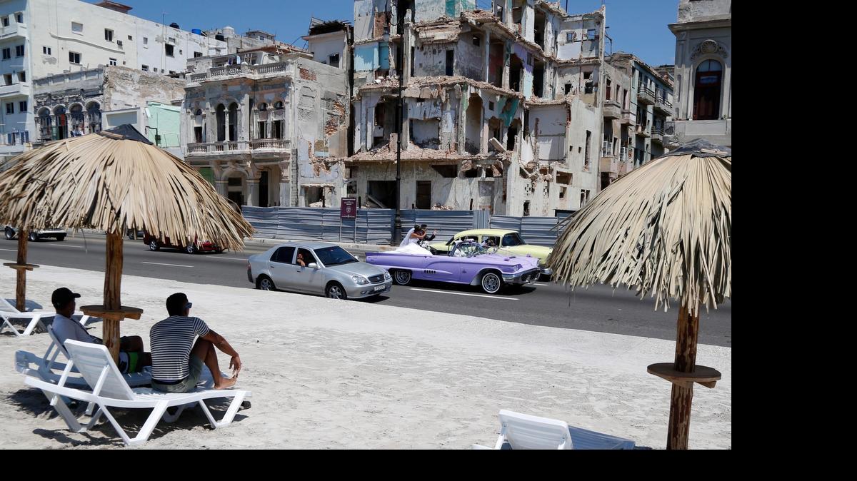 
ART IN HAVANA?: People sit on deck chairs on an artificial beach as a bride and groom ride a classic American convertible car on the Malecon in Havana, Cuba. The artificial beach is part of a collective artistic intervention named (R)Behind The Wall(R)for the 2015 Havana Biennial,which started on May 22 and runs through June 22.
