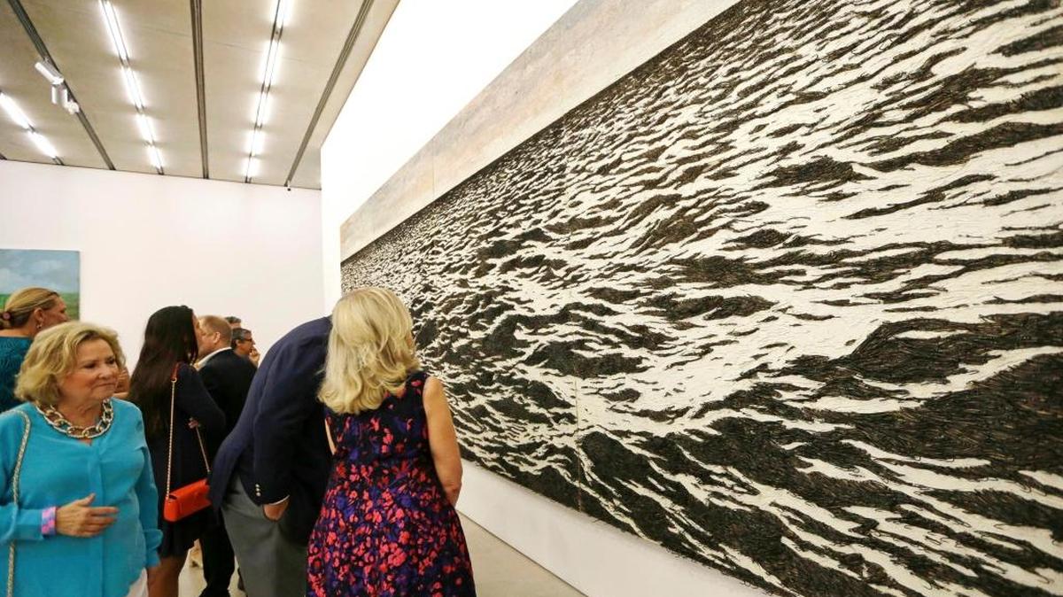 In this photo taken Thursday, June 8, 2017, visitors and guests look at the piece ‘Island (sea-escape)’ by Yoan Capote, a sculptor and painter who lives in Havana, at a private viewing at the Perez Art Museum in Miami. Four huge panels depict a choppy black sea. A closer look reveals that the choppy dark waters are in fact half a million fish hooks, sticking out from the canvas. in Miami.