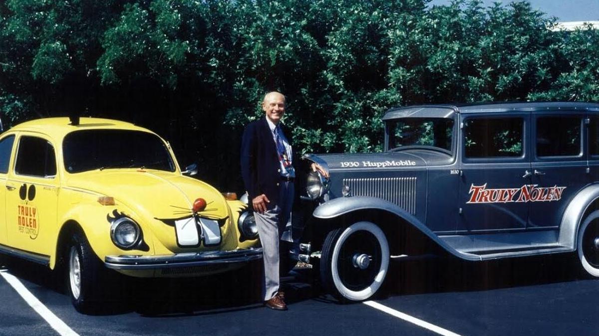 Truly David Nolen poses with two of the vehicles that made him famous: the Truly Nolen pest control company’s yellow VW bug “mouse car” with ears and tail and one of his antique cars bearing his name in Naples, where he has lived for 25 years.