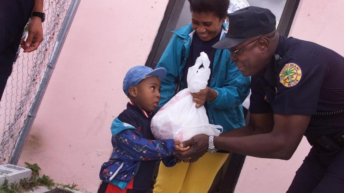 City of Miami police officer Harvey Nairn passed a turkey to Marie Loussaint and her then-2-year-old son Mykentor at the Little Haiti Net Service Center in November 2001. Nairn helped run the annual Turkey Give-Away by the City of Miami Police where more than 300 turkeys were given to families.