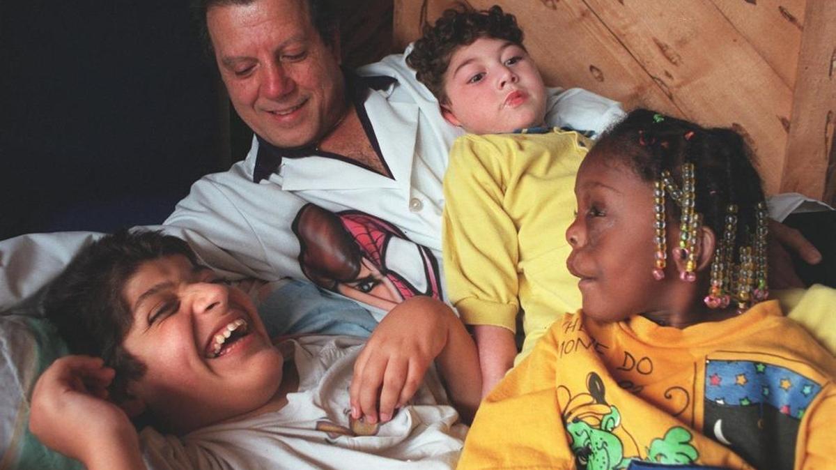 Dr. Michael Geraldi, at home with a few of his children, then numbering more than 40 in November 1996. At left was Jose, then 12, Adam, then 4, Meredith, then 3-1/2. The Geraldis, for years, have been the home for many children with acute physical problems.