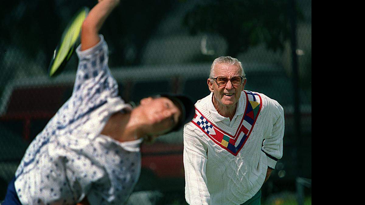 
EAGLE EYE: Saki Balafas would circle magazine photos of superstar tennis players’ racket and body positions so he could have his students at Moore Park in Allapattah and Tennis Villas in West Kendall mirror proper form. Here, in 1996, he watched as Milangela Morales practiced serves during a lesson.
