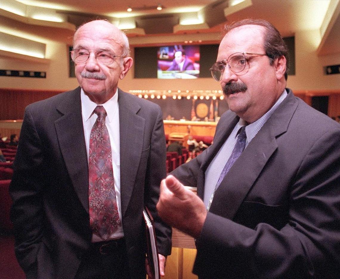 In 2001, Miami Springs Mayor John Cavalier Jr. (left) and Virginia Gardens Mayor Paul Bithorn-(right) discussed Miami International Airport issues at a Miami-Dade Commission meeting.