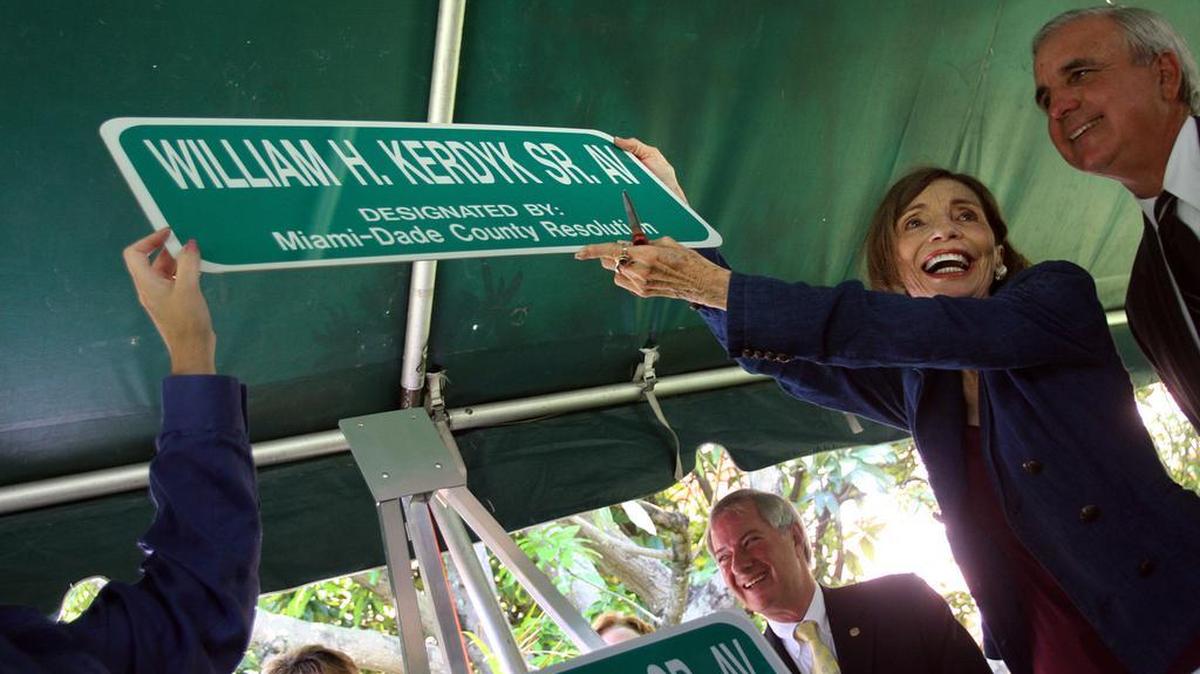 Family, friends and members of the local government joined on May 27, 2009, for the dedication of a portion of Douglas Road, between southwest Eighth and 22nd streets, to former Coral Gables Commissioner William H. Kerdyk Sr. Pictured are his wife Marlene Kerdyk, who holds up the street sign, as then-Miami-Dade County Commissioner Carlos Gimenez (now mayor) watches.