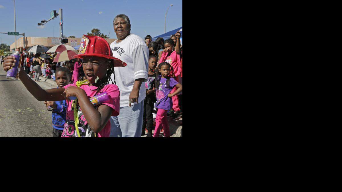 
Shakeria Williams, left, can not help spraying paraders with "silly string" as she and her family attends the Dr. Martin Luther King Day parade in 2014. The parade brought together Miami-Dade cities, their officials, various law enforcement agencies, various local government departments along with several school marching bands, and other civic organizations to celebrate and honor Dr. King on January 20, 2014.
