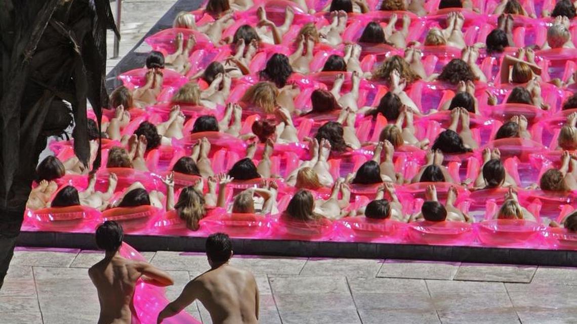 A nude woman grabs her pink raft and runs towards the Sagamore Hotel swimming pool filled with about 140 nude women on pink rafts Oct. 8, 2007. Spencer Tunick photographed hundreds of nude volunteers at the Sagamore Hotel on Miami Beach for an Art Basel installation.