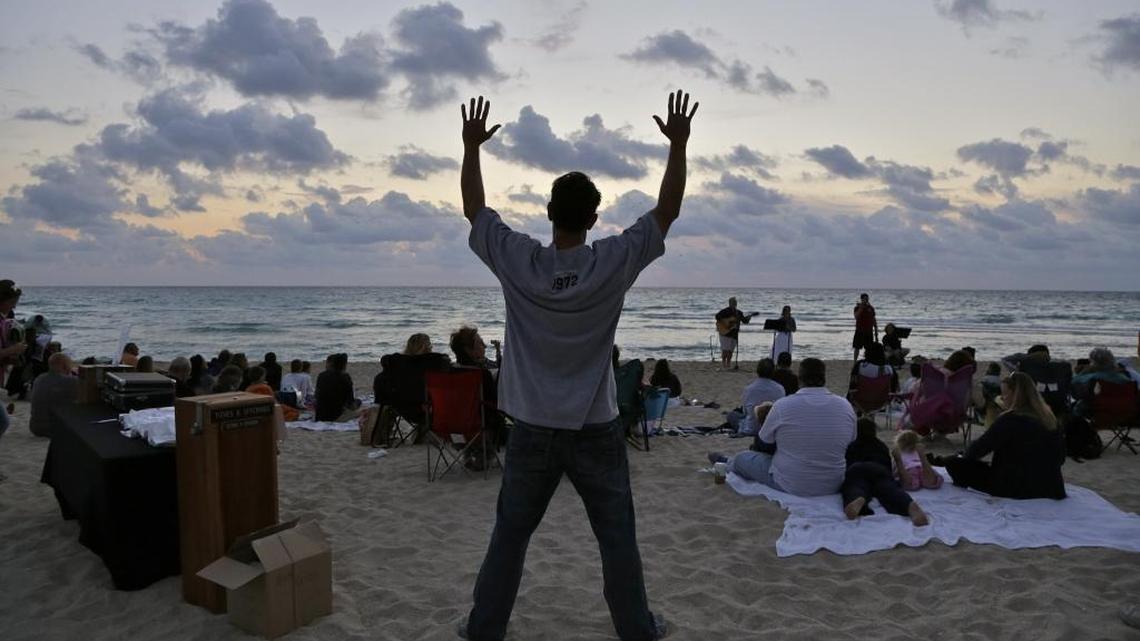 John Zinicola, 48, center, raises his hand in worship during the Calvary Chapel's Sunrise Easter Service. Members of New Life Missionary Baptist Church of Liberty City and Calvary Chapel of Miami Beach both held baptism and Easter Sunrise Services at the beach behind the Miami Beach's band shell on Easter Sunday, March 31, 2013.