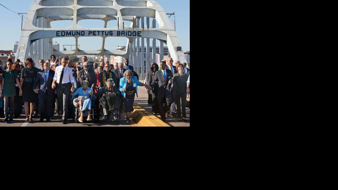 
President Barack Obama, fourth from left, walks holding hands with Amelia Boynton, who was beaten during "Bloody Sunday," as they and the first family and others including Rep. John Lewis, D-Ga, left of Obama, walk across the Edmund Pettus Bridge in Selma, Ala. for the 50th anniversary of the landmark event of the civil rights movement, Saturday, March 7, 2015. At far left is Sasha Obama and at far right is former first lady Laura Bush. 

