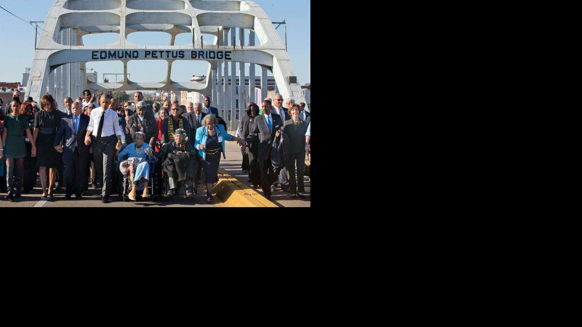 
President Barack Obama, fourth from left, walks holding hands with Amelia Boynton, who was beaten during "Bloody Sunday," as they and the first family and others including Rep. John Lewis, D-Ga, left of Obama, walk across the Edmund Pettus Bridge in Selma, Ala. for the 50th anniversary of the landmark event of the civil rights movement, Saturday, March 7, 2015. At far left is Sasha Obama and at far right is former first lady Laura Bush. 
