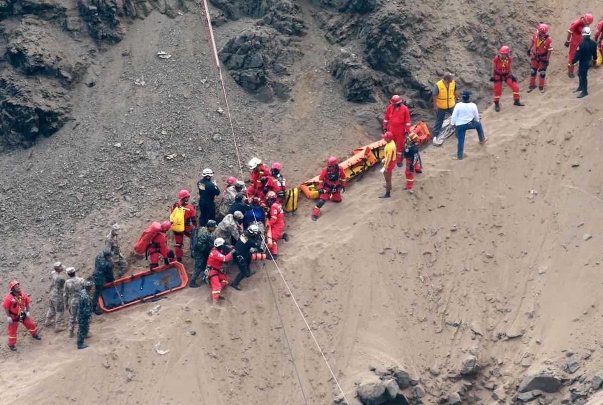 In this photo provided by the government news agency Andina, rescue workers surround an injured man on a stretcher who was lifted up from the site of a bus crash at the bottom of a cliff, after the bus was hit by a tractor-trailer rig in Pasamayo, Peru, Tuesday, Jan. 2, 2018. A Peruvian police official says at least 25 people died, and that there were more than 50 people on the bus.