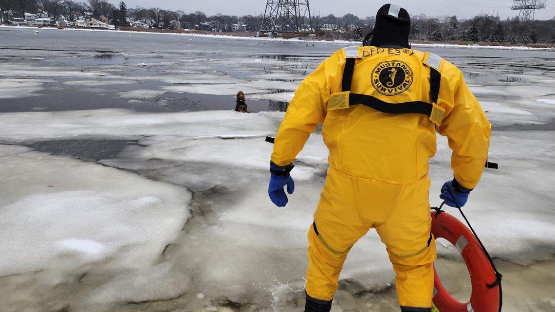 Dog clings to broken ice with front paws on frozen Massachusetts river as firefighter comes to rescue.
