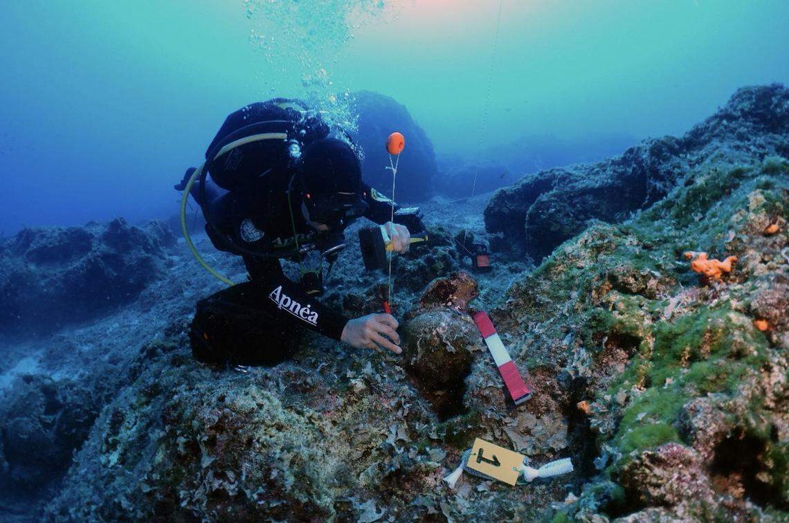 A diver inspects an underwater artifact