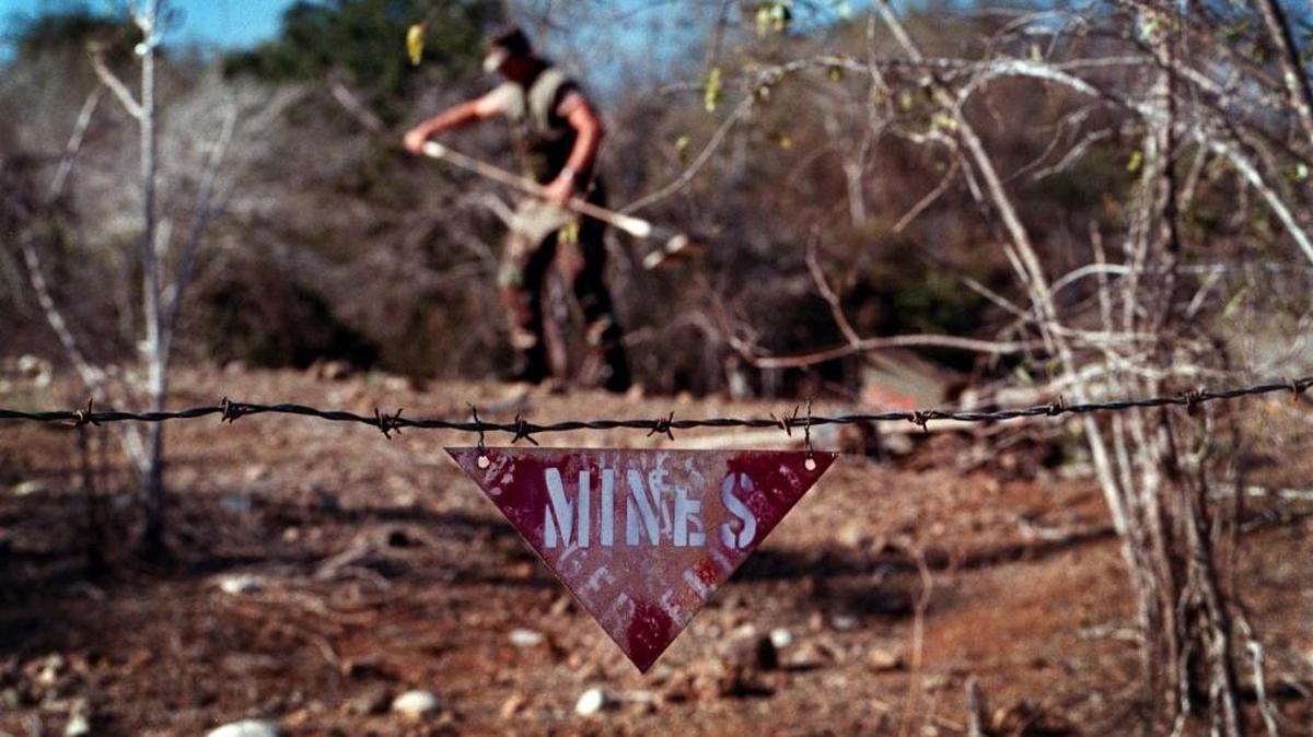 .U.S. Marine Master Sgt. Joseph Atkins listens for land mines on a practice field with a metal detector on March 18, 1999 at Guantánamo Bay Navy base.