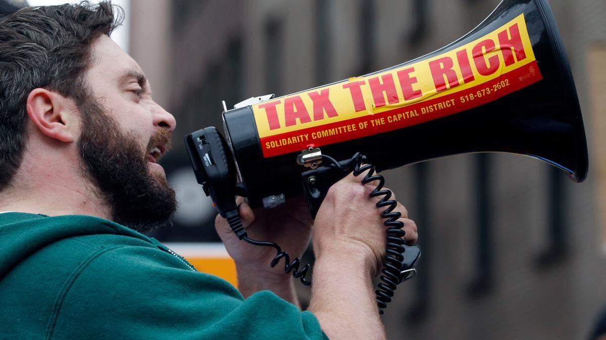 A majority of Americans across partisan and racial lines support raising taxes on the wealthy and large corporations, according to a new poll. (AP Photo/Mike Groll)
