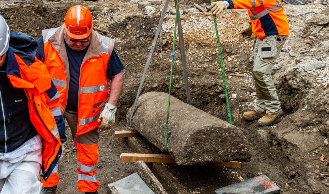 Workers open the lid of a stone sarcophagus.