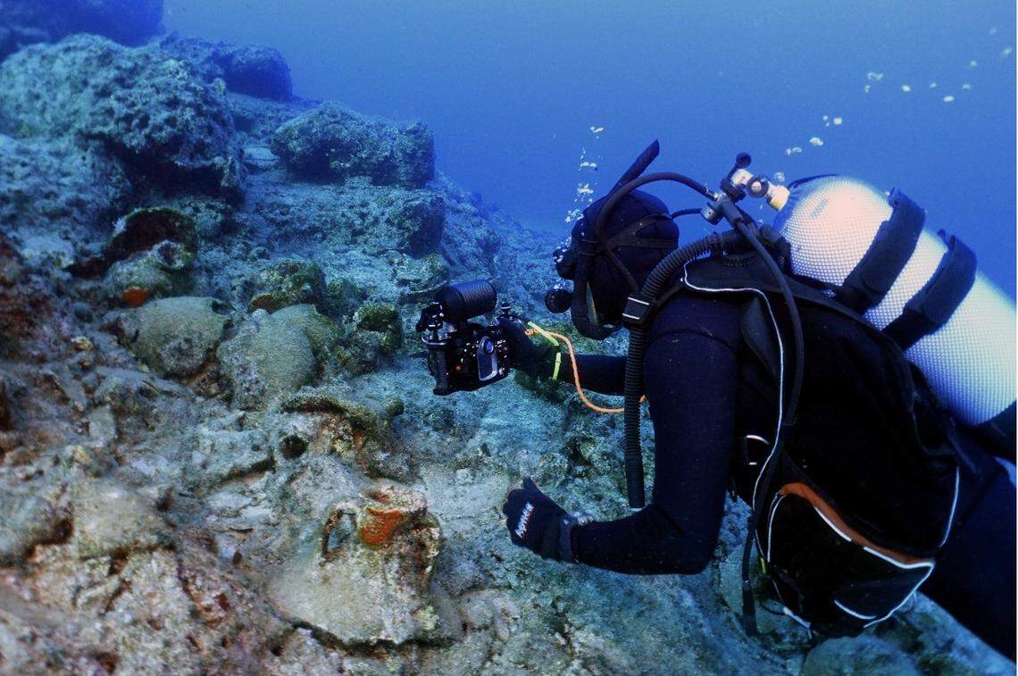 Diver swims near cluster of broken vessels