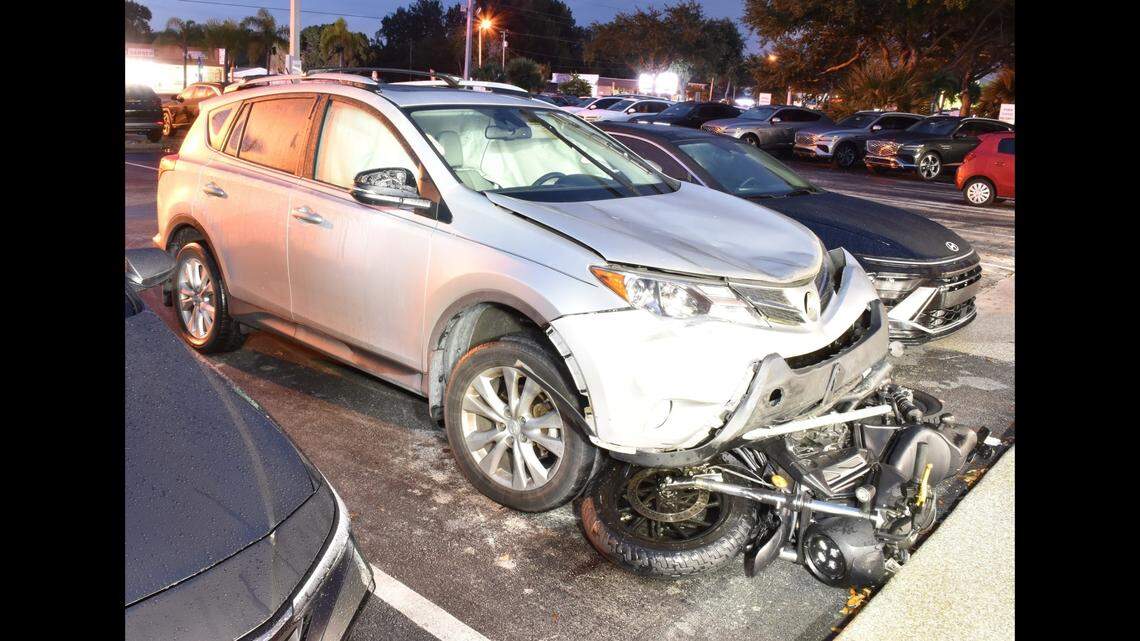 A driver was captured on a security camera in a parking lot trying to remove a motorcycle stuck under her SUV following a crash, police said.
