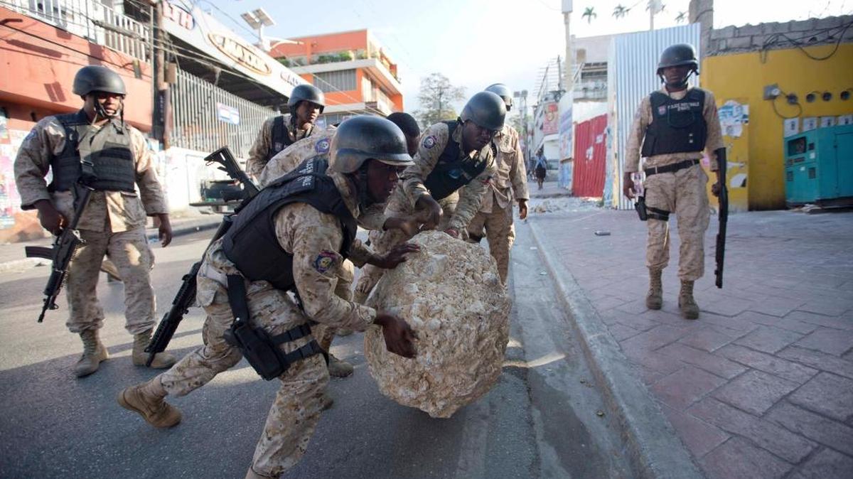Haiti National Police officers remove a rock used as a street barricade by demonstrators after a protest against the results of Oct. 25 elections, in Port-au-Prince, Haiti, Wednesday, Nov. 18, 2015.