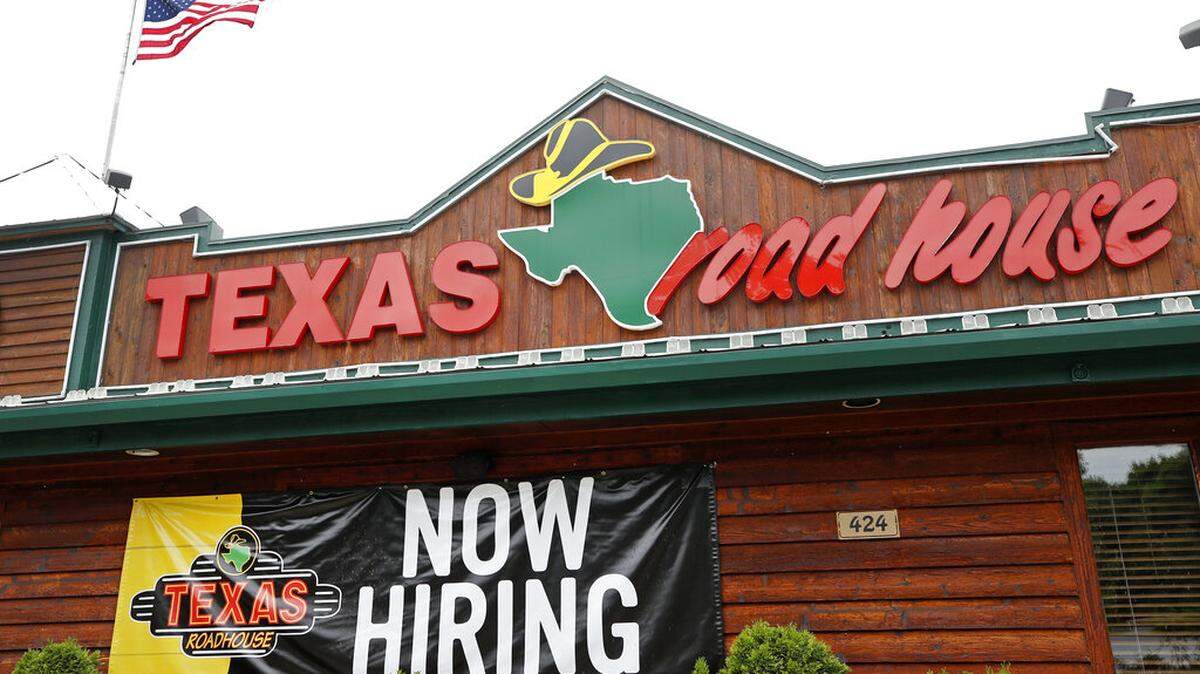 Many restaurants have continued hiring to relieve prolonged staffing shortages. Here a Texas Roadhouse restaurant has a large “now hiring” sign hanging on the side of its building.