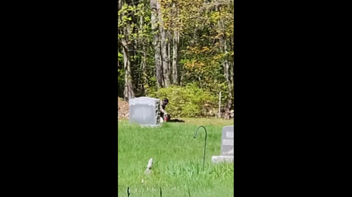 A poacher is seen wrangling a turkey behind a headstone, officers said.