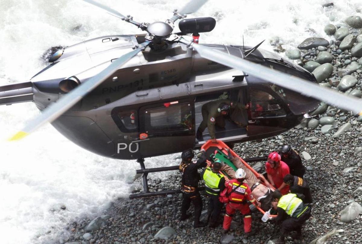 In this photo provided by the government news agency Andina, rescue workers load an injured man on a stretcher after he was retrieved from a bus that fell off a cliff after it was hit by a tractor-trailer rig, in Pasamayo, Peru, Tuesday, Jan. 2, 2018. A Peruvian police official says at least 25 people died, and that there were more than 50 people on the bus.
