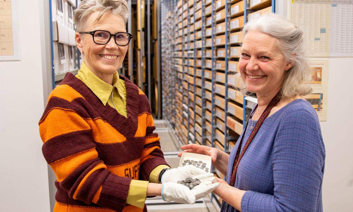 Archaeologists hold the the 800-year-old silver coins.