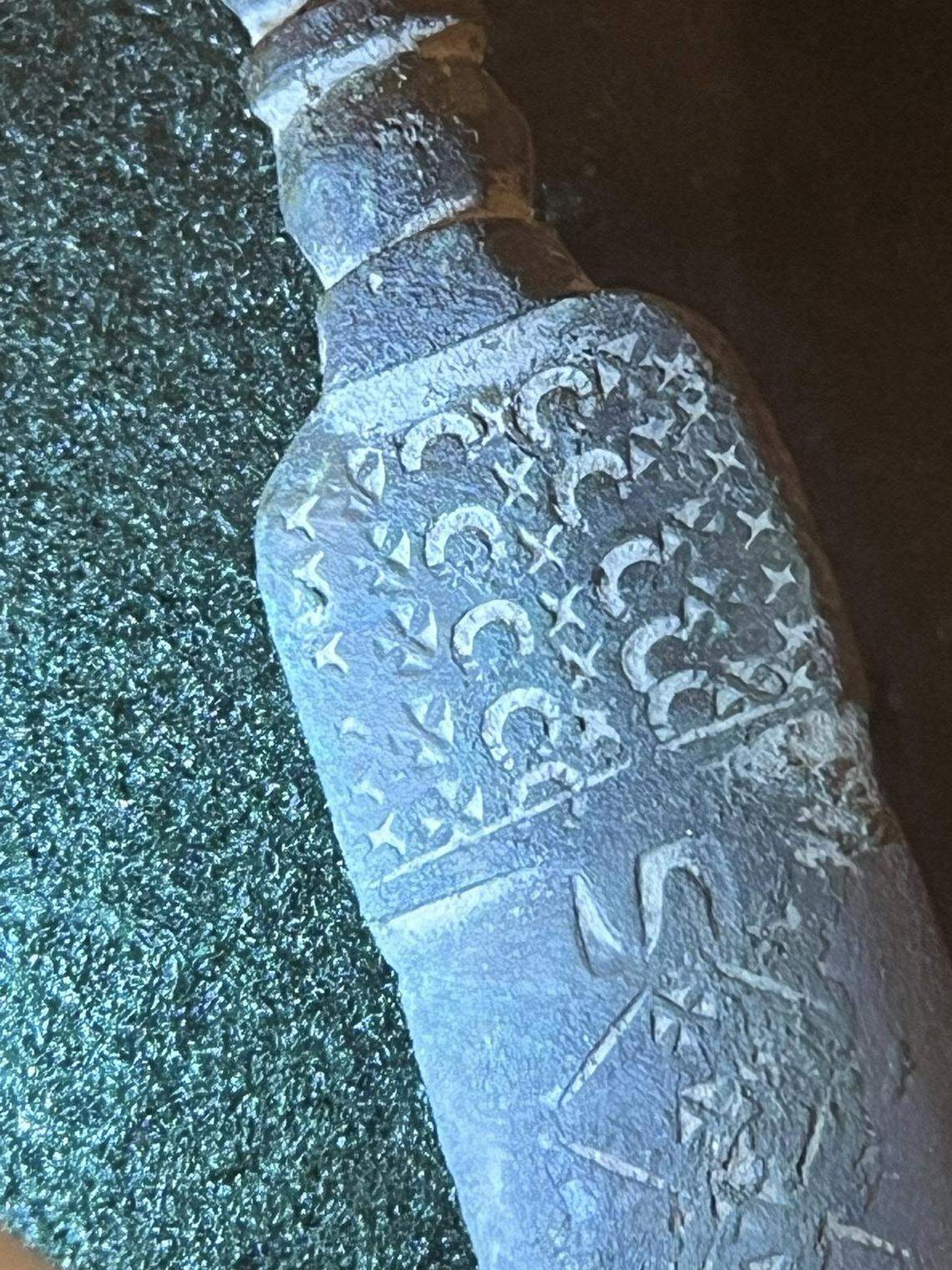 A close-up photo shows the design on the dagger’s blade.