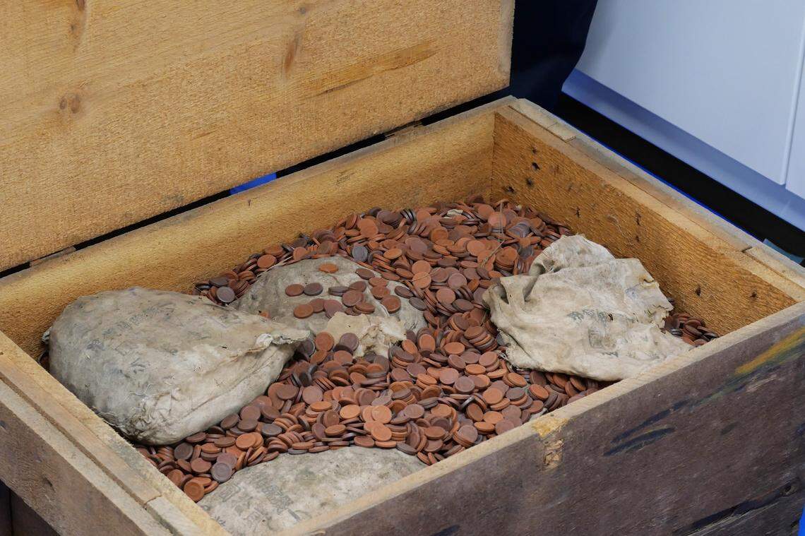 A wooden box with some loose “phantom” coins and some bagged coins.