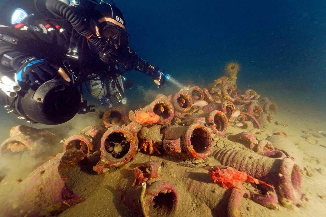 Divers illuminate the pile of ancient Roman jars.