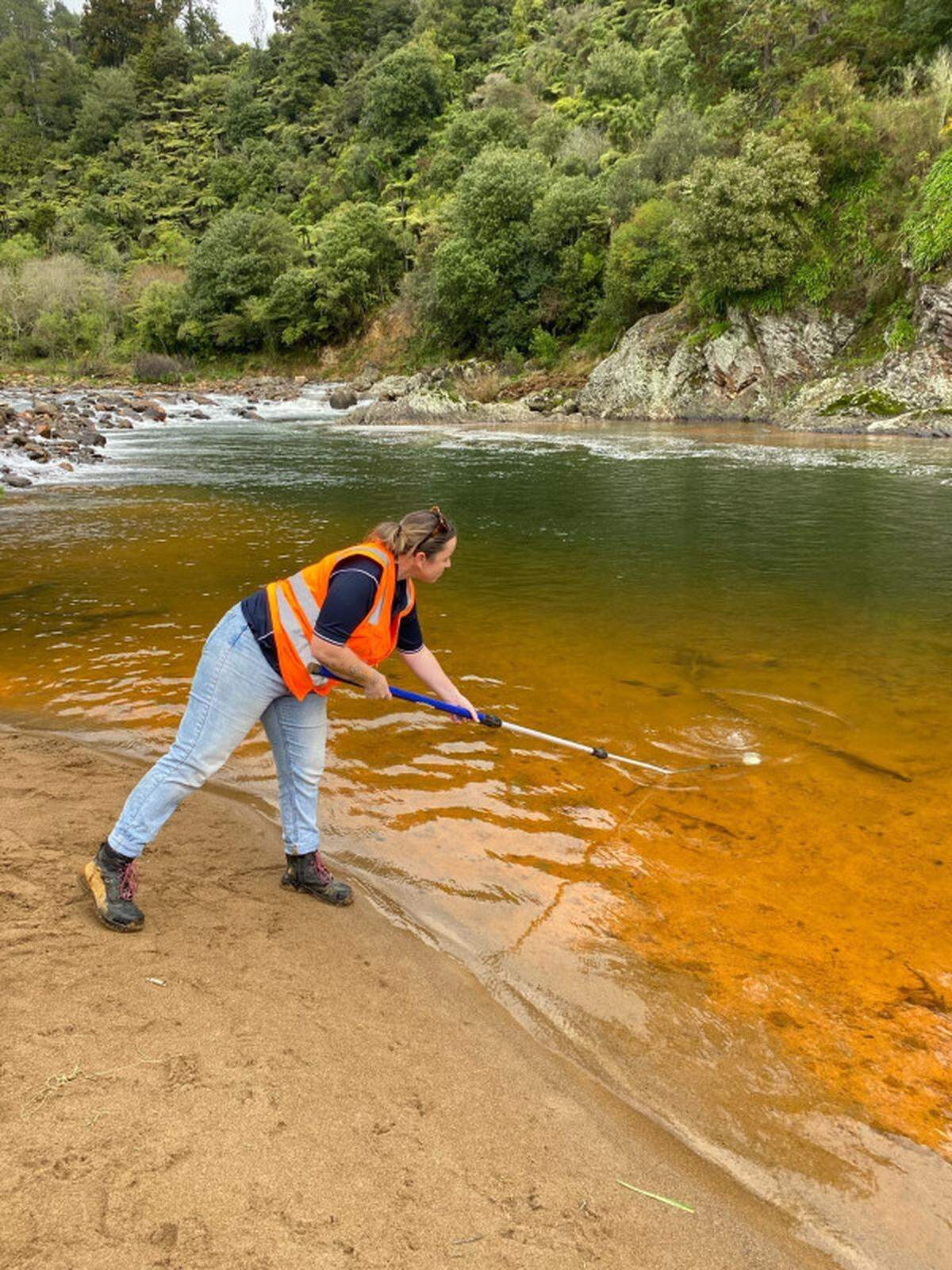 An official takes a sample of the discolored water.