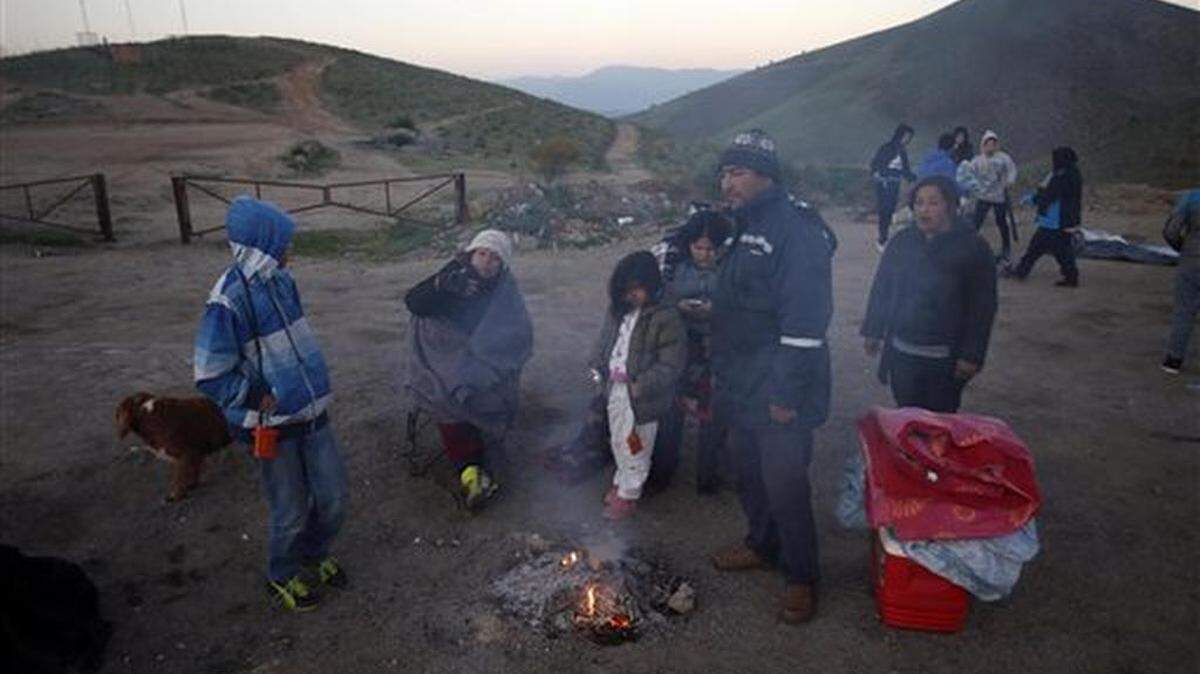 A family allows their campfire to go out after spending the night on the top of this hill on the outskirts of Illapel, Chile, early Thursday, Sept. 17, 2015. Thousands of residents of this small city in northern Chile slept outside after a powerful earthquake late Wednesday destroyed their homes, forced more than 1 million to evacuate and killed at least eight people in the quake-prone South American nation.