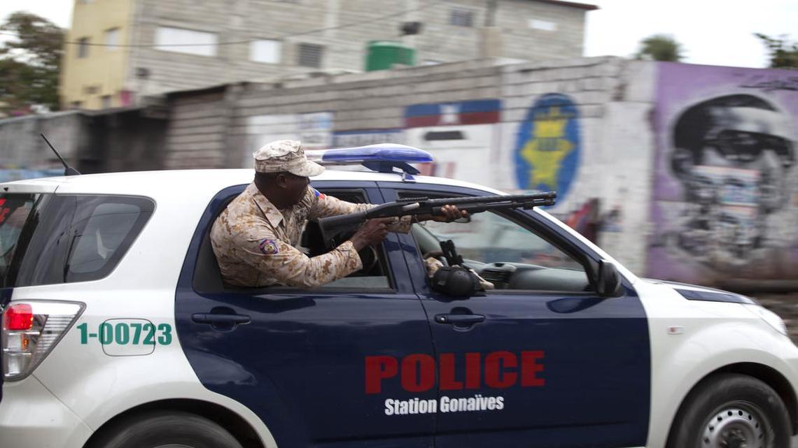 A national police officer fires birdshot at demonstrators during a street protest after it was announced that the runoff Jan. 24, elections had been postponed, in Port-au-Prince, Haiti, Friday, Jan. 22, 2016. The Provisional Electoral Council in Haiti has postponed the election amid escalating protests by the opposition, which claims the first round was marred by fraud in favor of a government-backed candidate.