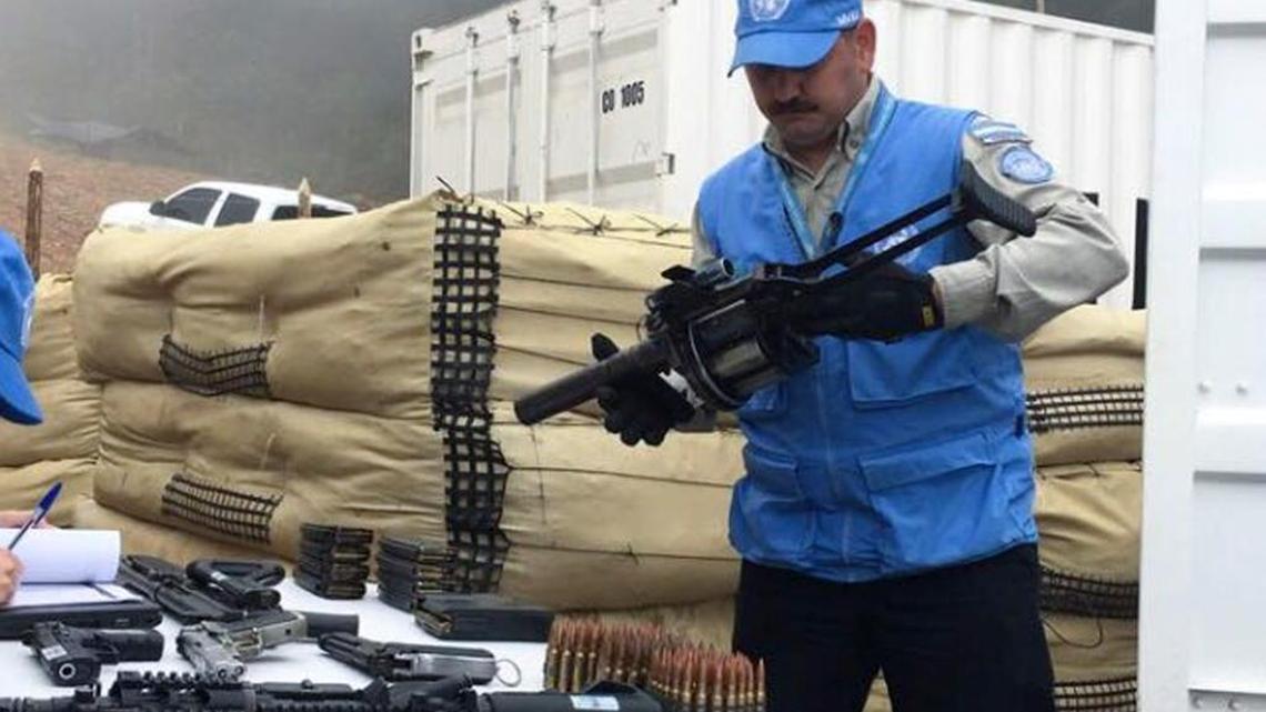 In this photo released by the United Nations mission based in Colombia, a member of the U.N. monitoring mission for the Colombian peace process holds a weapon handed over by rebels of the Revolutionary Armed Forces of Colombia, or FARC, as part of last year's peace agreement at the La Elvira temporary camp in Buenos Aires in southern Colombia, on June 13, 2017.