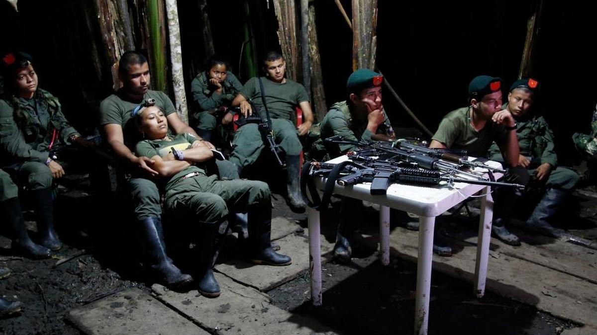 In this Aug. 11, 2016 photo, rebels of the 48th Front of the Revolutionary Armed Forces of Colombia watch a nightly newscast on a television at their encampment in the southern jungles of Putumayo, Colombia.
