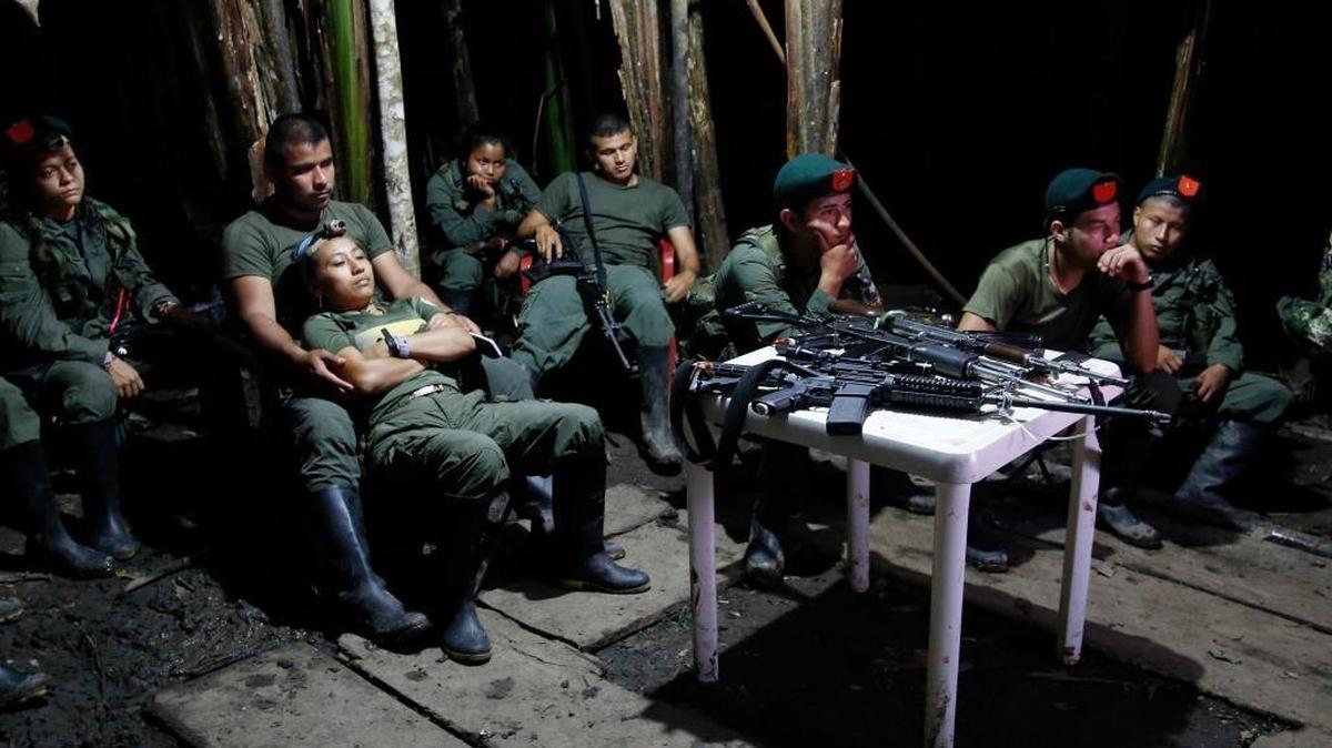 In this August photo, rebels of the 48th Front of the Revolutionary Armed Forces of Colombia watch a nightly newscast on a television at their encampment in the southern jungles of Putumayo, Colombia.